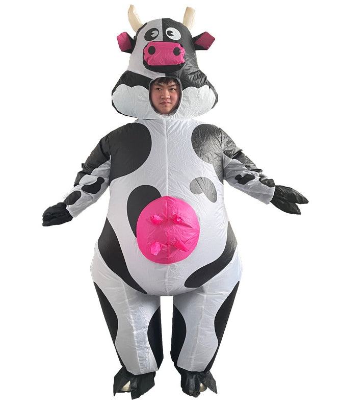 Adult wearing white and black spotted inflatable cow costume with pink udder and googly eyes