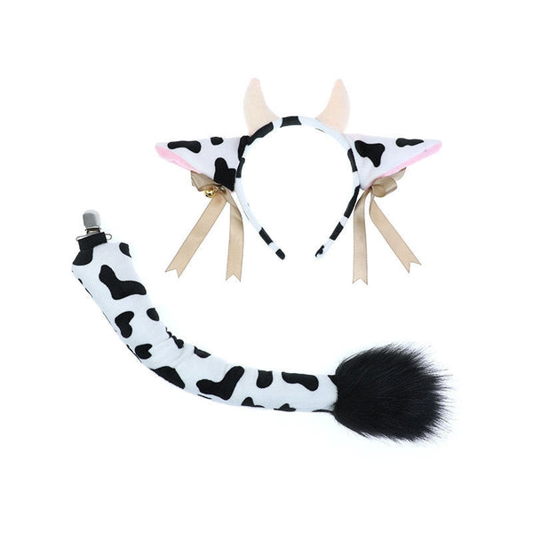 Cow ears headband with black and white spots, pink inner ears, and brass bells on white background