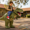 Cheerful Australian kid in a green inflatable Ride-On T-Rex costume on the schoolyard — the riding illusion at perfect side angle