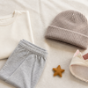Folded neutral clothes, a soft beanie, a small crown headband and a removable fabric star pin