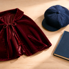 Burgundy child-size cape, navy cap and closed unbranded book arranged for a Book Week character clue