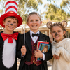 Three Australian kids in book week costumes — Cat in the Hat, child conductor, and Hush from Possum Magic