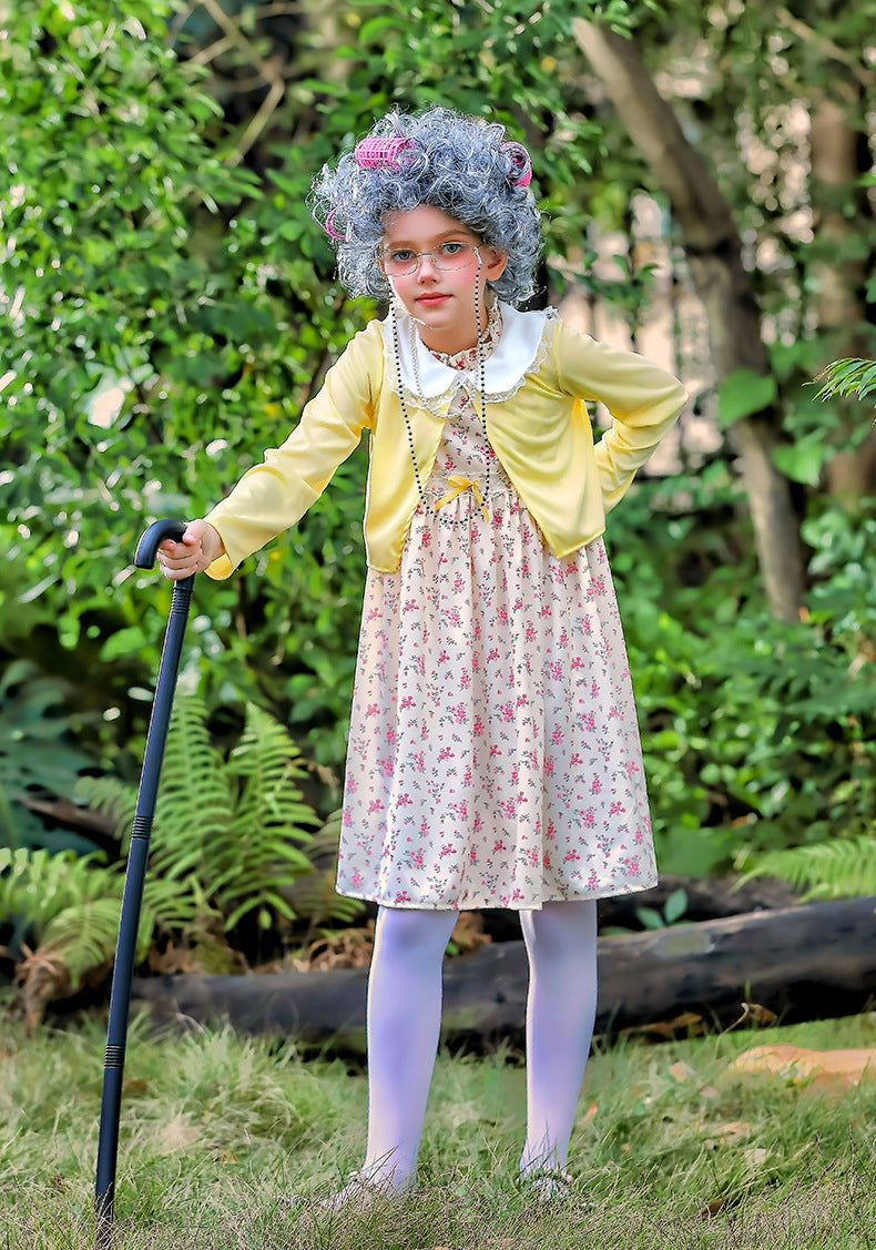 Child wearing grandma costume with floral dress, yellow jacket, and grey curly wig with pink rollers